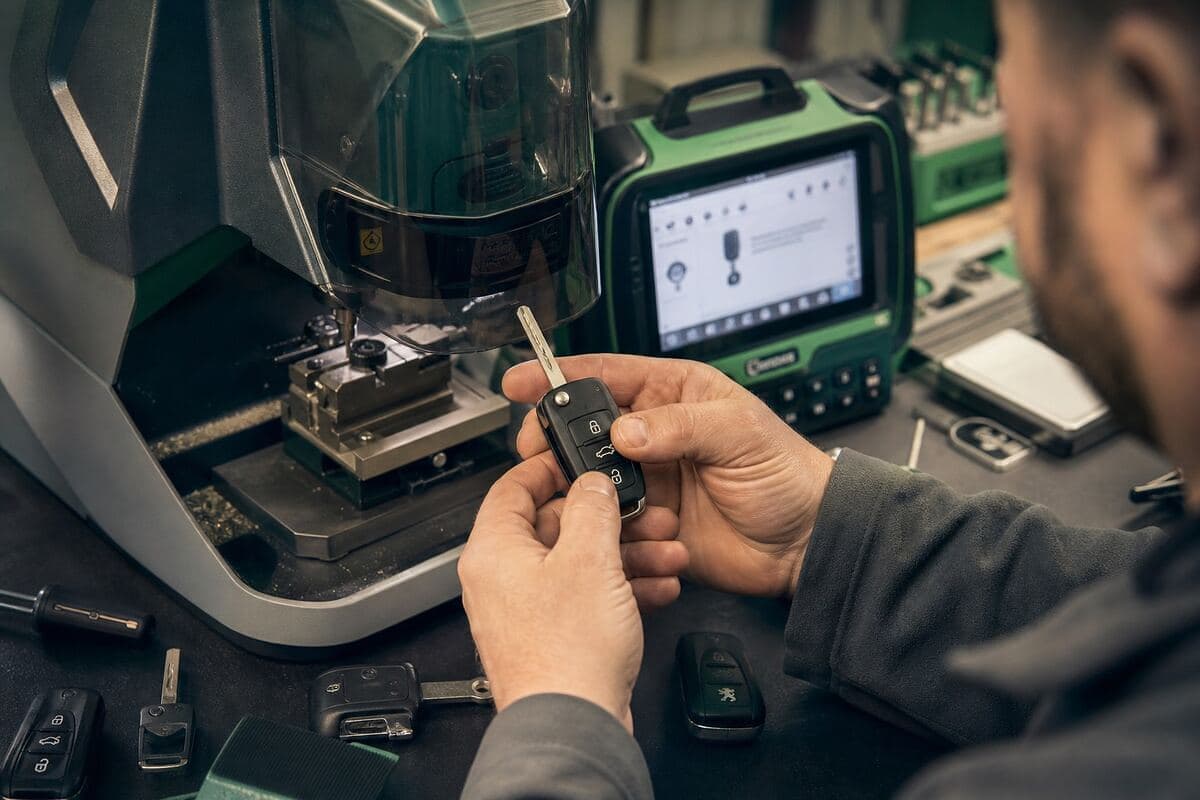 Taille d'une clé de voiture pliable sur la machine de l'atelier, boîtier de programmation à côté